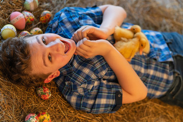 teen boy lying in the manger with yellow ducklings on her stomach and shows a heart symbol with hands