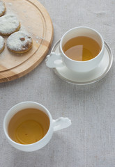 White cup of tea and homemade cookies on wooden board on linen tablecloth. Copy space. Food frame