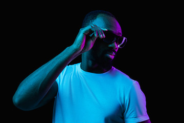 The retro wave or synth wave portrait of a young happy smiling african man in sunglasses at studio....