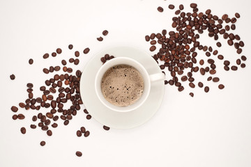 White cup with black classic coffee and a saucer among coffee grains. Top view, isolated on white background