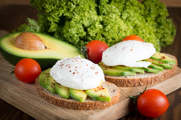 macro photo of sliced avocado with tomatoes on a cutting board on wooden background. Healthy organic food concept.