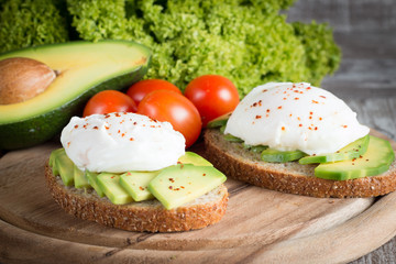 macro photo of sliced avocado with tomatoes on a cutting board on wooden background. Healthy organic food concept.