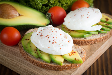 macro photo of sliced avocado with tomatoes on a cutting board on wooden background. Healthy organic food concept.