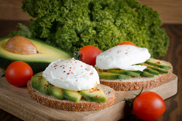macro photo of sliced avocado with tomatoes on a cutting board on wooden background. Healthy organic food concept.