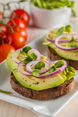 macro photo of sliced avocado with tomatoes on a cutting board on wooden background. Healthy organic food concept.