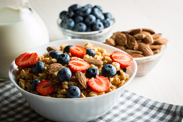 Healthy breakfast concept with oat flakes and fresh berries on rustic background. Food made of granola and muesli. Healthy banana smoothie with blackberries, honey and milk.