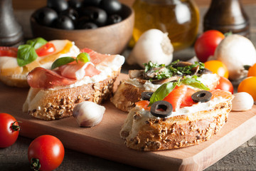 Italian tomato and cheese bruschetta. Tapas, antipasti with chopped vegetables, herbs and oil on grilled ciabatta and baguette bread.