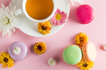 Still life and food photo of cake macarons in a gift box with flowers, a cup of tea on light background. Sweets and desserts concept of macaroons.