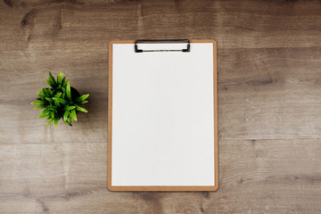 Clipboard with white sheet on wooden background