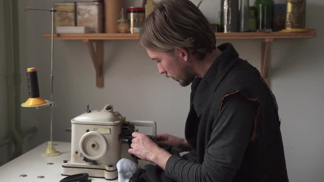 Young man tailor sewing fur on furrier machine