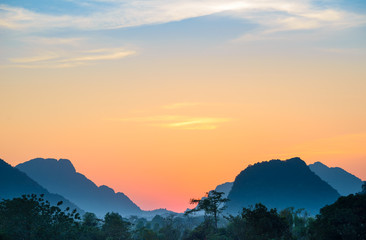 Vang Vieng backpacker travel destination in Laos, Asia. Sunset over scenic cliffs and rock pinnacles, rice paddies valley, stunning landscape.
