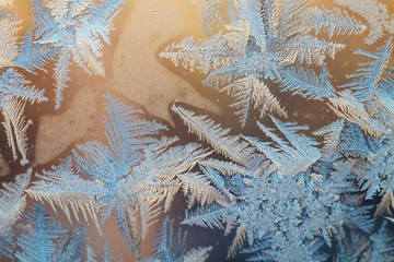 The texture of the frosty patterns. Winter frosty blue patterns on glass pink background