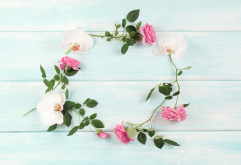 Top view of floral frame consists of roses and orchids flowers on wooden background in shabby chic style