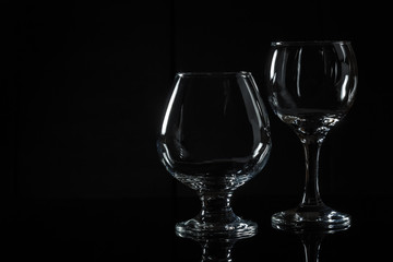 Empty glasses made of transparent glass on a black background. Reflection in a glass base.