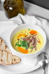 Corn soup puree with toast in white bowl on white wooden background