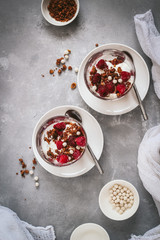 Flat lay with glasses of layered granola and yogurt with raspberries on a dark background