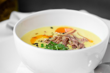 Corn soup puree with toast in white bowl on white wooden background, close up