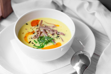 Corn soup puree with beef in white bowl on white wooden background