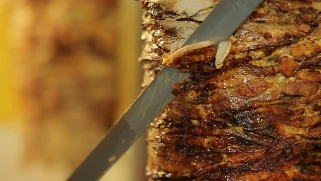 A cook cuts meat to make shawarma, gyros, doner kebab. Cooking meat on a skewer