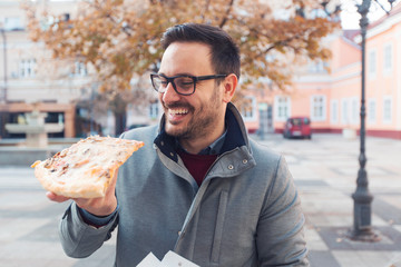 Man eating pizza outdoors.