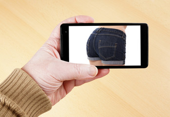 male hand holding smart phone showing sexy photo of female butt in hot pants