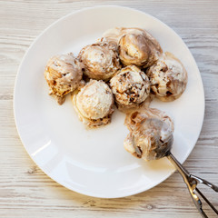 Ice cream in white round plate with spoon for ice cream, overhead view. From above, flat lay.