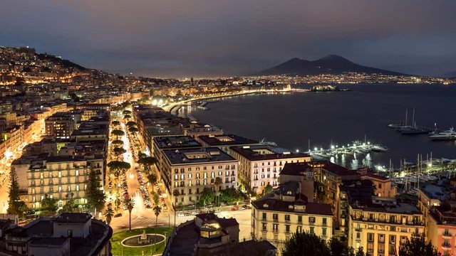Night view of Naples, Italy. Evening time lapse of illuminated Naples with old houses, traffic and vesuvius volcano