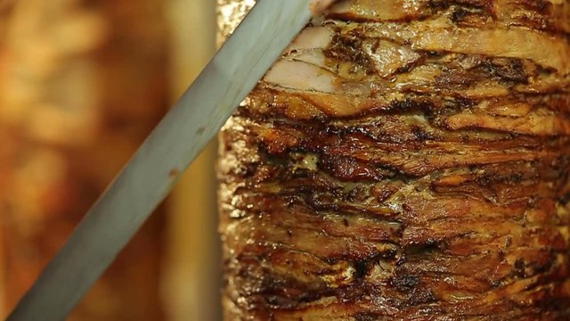 A cook cuts meat to make shawarma, gyros, doner kebab. Cooking meat on a skewer