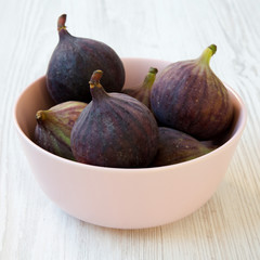 Fresh figs in a pink bowl on a white wooden background, side view. Close-up.