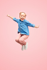 Young happy caucasian teen girl jumping in the air, isolated on pink studio background. Beautiful...