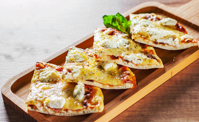 sliced Pizza with Mozzarella cheese, Tomatoes, pepper, Spices and Fresh Basil. Italian pizza. Pizza Margherita or Margarita on wooden table background