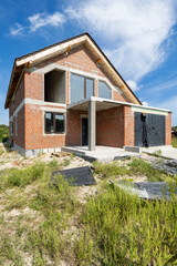 Fototapeta na wymiar Unfinished house with brick facade and plastic wingows