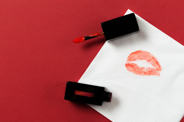 white paper napkin with lipstick and kiss on red background.
