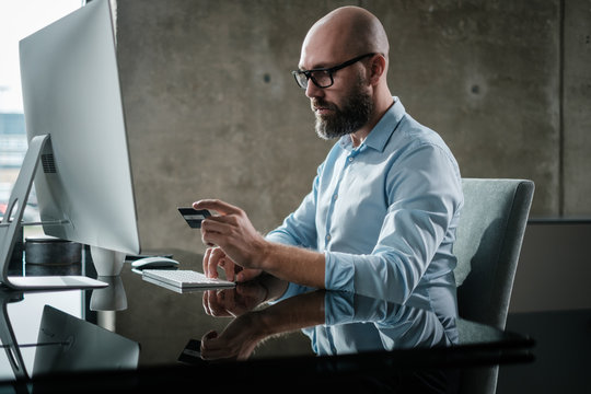 Middle-aged designer paying online in office