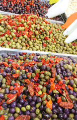 tray filled with black and green olives with peppers for sale in the market stall