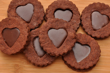 Chocolate chip cookies in the shape of a heart with toffee, on wooden background.