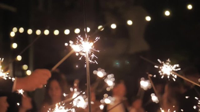Crowd celebrate at dark evening. Festival fire firework. Friends have fun in group. Slow motion