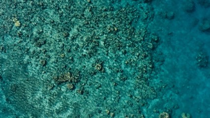 stunning aerial drone image of a a small fishing boat entering an a sea ocean anchorage in a channel next to a coral reef in crystal clear azure blue water at a remote isolated tropical island