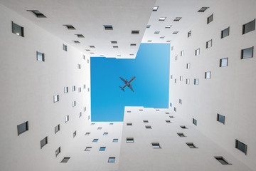 Fototapeta premium airplane in sky above building court - plane over courtyard
