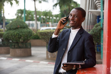 portrait of young african man in mobile phone, happy.