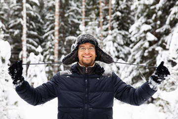 Fototapeta na wymiar Man in fur winter hat with ear flaps smiling portrait. Extreme in the forest