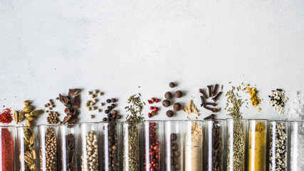 Various dry spices in glass tubes and spilled on gray background. Copy space. top view