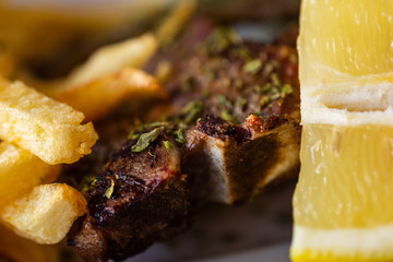 Delicious Serving Of Grilled Large T-Bone Steak Seasoned With Herbs By French Fries And Lemon Slice