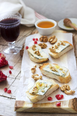 Fototapeta na wymiar Sandwiches with blue cheese, pomegranate, honey and nuts served with red wine. Rustic style.