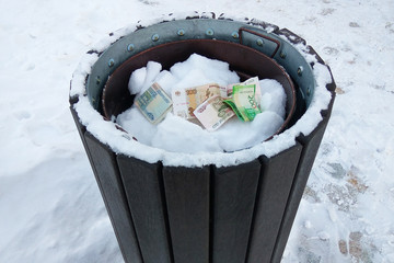 Russian rubbles in the trashcan in winter on white snow background. Concept of money waste, inflation, devaluation and currency depreciation, bad purchases and winter energy economy