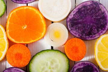 sliced fruits and vegetables on white wood table background