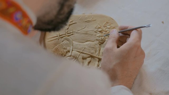 Professional male potter making clay stamp picture. Handwork, crafting and traditional arts concept