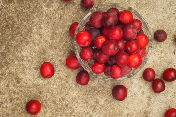 Mature red plum in a crystal vase on the background of concrete. View from the top