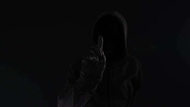 Cybercrime concept with faceless hooded male person, low key footage with digital glitch effect
