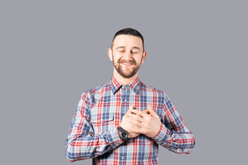 Body language concept. Young handsome man with facial hair posing over gray wall showing emotions. Portrait of masculine bearded male, wearing slim fit checkered shirt. Isolated background, copy space